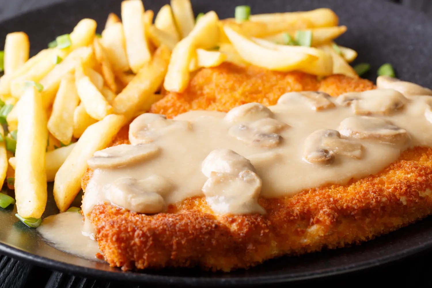 Champions Restaurant und Sportsbar - Genießen Sie frisch zubereitete Speisen, kühle Getränke - Jägerschnitzel mit Pommes frites und Champignons (Makroaufnahme, horizontal).