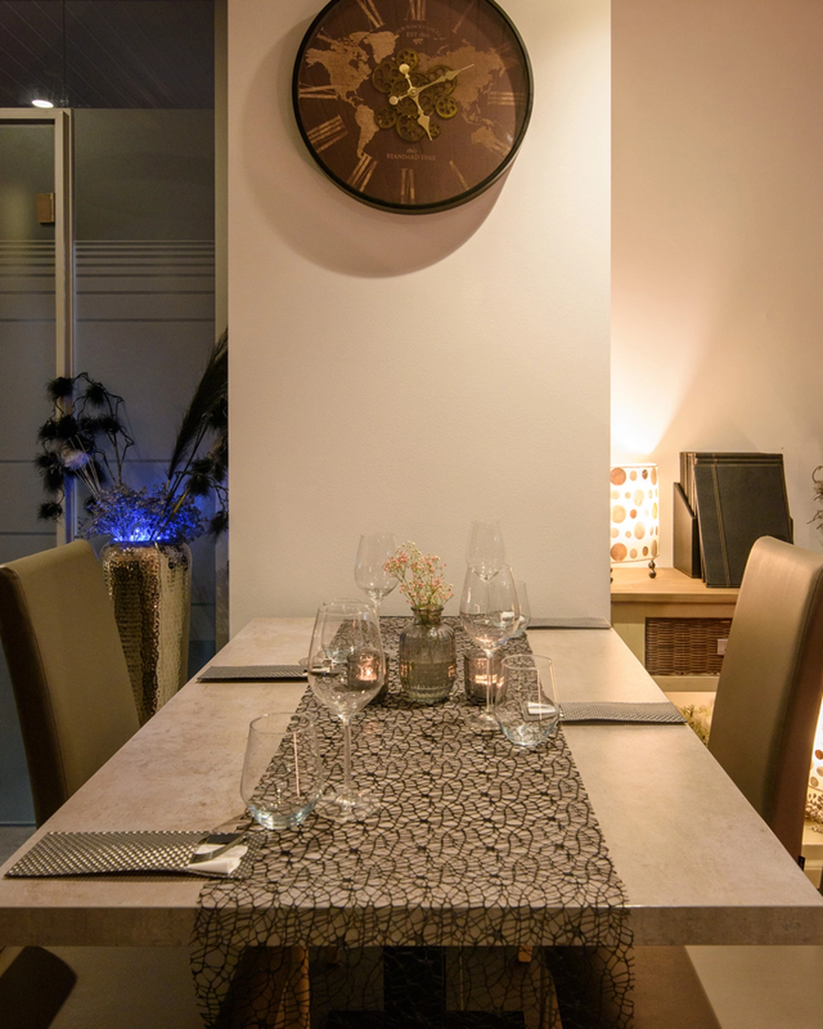 Champions Restaurant und Sportsbar - Genießen Sie frisch zubereitete Speisen, kühle Getränke - Ein Esstisch, gedeckt für ein intimes Abendessen mit Weingläsern, Kerzen und einem kleinen Blumenarrangement in einem gemütlichen, schwach beleuchteten Raum.